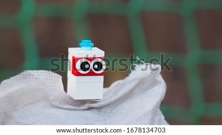 a strange unknown but very cute plastic creature with big eyes sits on a bag of sugar against a green grid