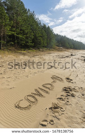 Sign about corona virus on the sand on beach in spring
