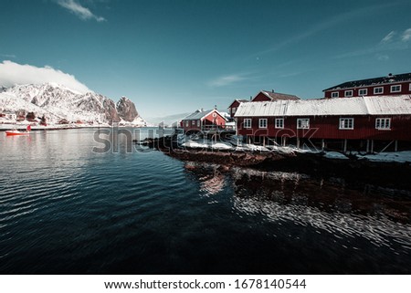 Morning in Reine, unbelievable view on small fishing village in Lofoten, Norway, Epic snowy mountains and red cabins with water, beautiful background picture from wild nature, clear sky and clouds 