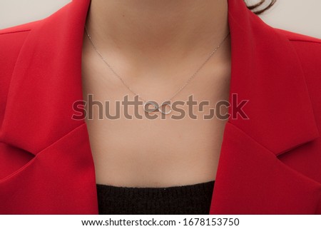 elegant lady in black blouse, red jacket and figured necklace hanging around her neck