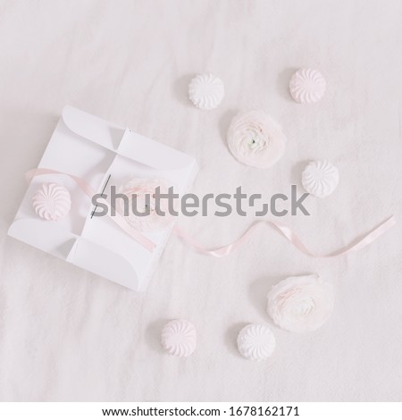 Gift or present box  with pink ribbon and flowers on white background top view. Birthday, wedding or holiday background. pastel colors. Flat lay styling. Copy space for text.