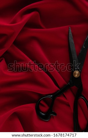 Red fabric on the table with black professional scissors, cutting fabric