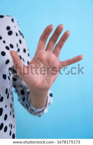Female hand showing stop sign on a blue background in studio