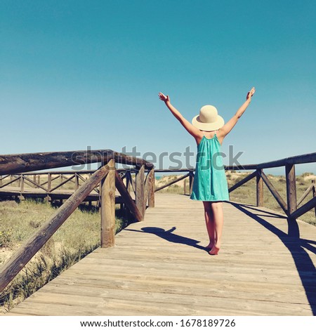 holidays beach background with girl on a wooden bridge near the sea