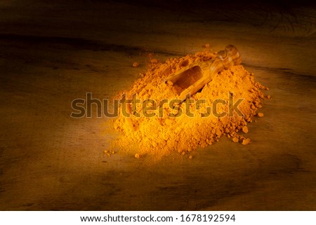 Turmeric powder and roots on a dark wooden surface