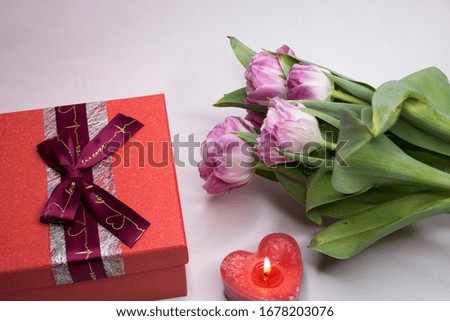 Gift box with bow. Holiday. Candle with fire. Close-up. The color is red, pink.