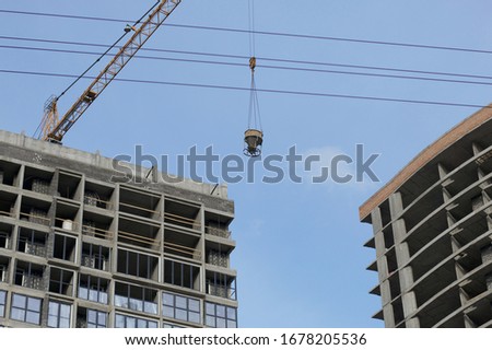 High-rise building under construction. Reinforced concrete frame. Start of installation of double-glazed windows. Visible construction cranes.