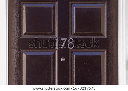 House number 178 on a black wooden front door