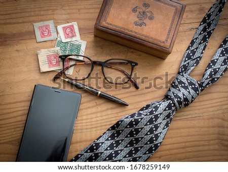 masculine pine wood flat lay with leather box, black phone, black neck tie and other men's accessories for a fathers day holiday look