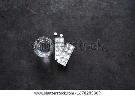 Tablets and glass of water on a concrete background.