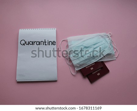 Masks, passports, and a Notepad with the text Quarantine on a pink background. Flat lay 
