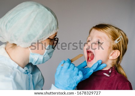 Coronavirus. Nurse or doctor in a protective suit and mask checks and looks the sick girl's throat with virus symptom. Epidemic outbreak concept.