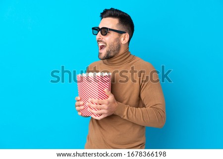 Young handsome man with 3d glasses and holding a big bucket of popcorns