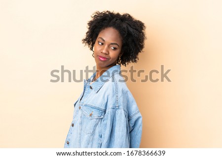 Young African American woman isolated on beige background . Portrait