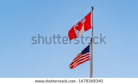 USA And Canada Flags Isolated On Blue Sky.