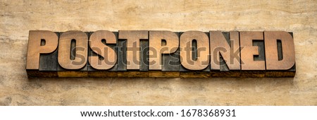 postponed  - word abstract in vintage letterpress wood type, event postponement due to covid-19 coronavirus pandemic, social distancing concept Royalty-Free Stock Photo #1678368931