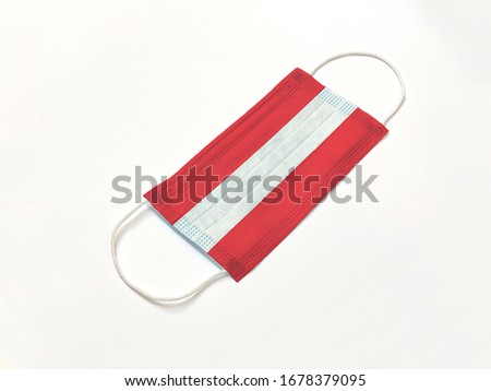 Concept. Conceptual: Disposable medical surgical face mask with Austria country flag superimposed on it, on white background. Protection against Covid-19 coronavirus outbreak.