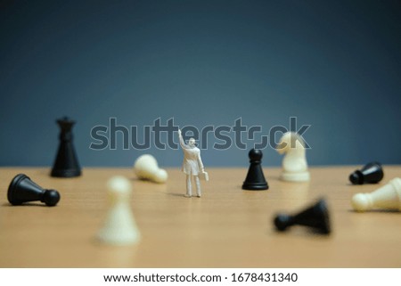 Business strategy conceptual photo - Miniature businessman pointing up in the middle of a chess piece that falls on the chessboard