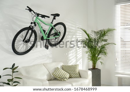 Stylish living room interior with white sofa and green bicycle
