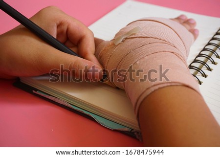 The boy drawing a hand injury that was wrapped with a bandage.