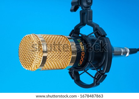  Studio microphone for recording podcasts, songs, and radio programs on a blue background with a place for inscription. copyspace