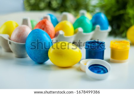multicolored painted eggs for Easter lie in an egg mold with green twigs in the background