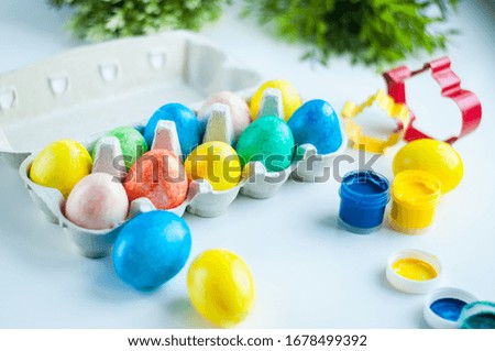 multicolored painted eggs for Easter lie in an egg mold with green twigs in the background