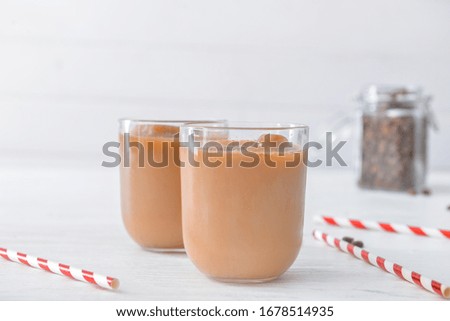 Glasses of tasty iced coffee on white table