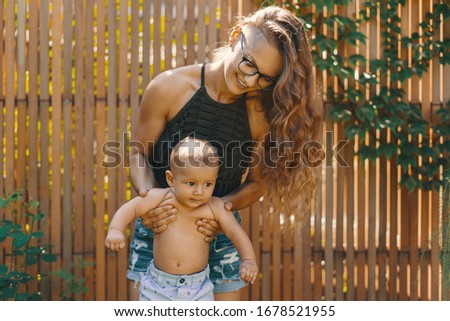 Young mother doing baby yoga for her son in the backyard garden