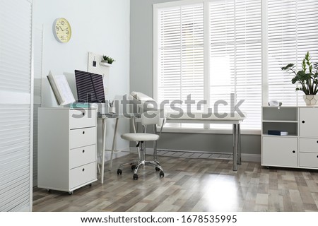 Modern medical office interior with computer and examination table Royalty-Free Stock Photo #1678535995