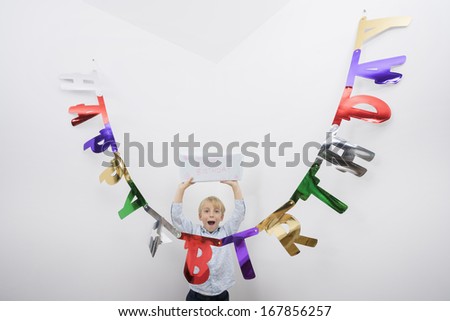 Portrait of boy with mouth open holding birthday gift over head