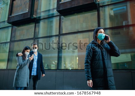 Young girl wearing a protective mask in the city talking on a phone. Group of people using telephone wearing pollution masks. 