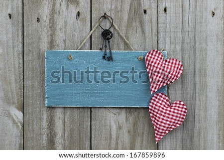 Antique blue sign hanging on wood door with hearts and iron keys