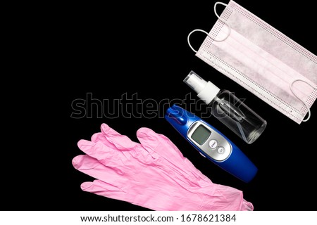 Sanitizer bottle, Medical surgical mask, modern thermometer and lab gloves - Virus protection equipment on black background. COVID middle East respiratory syndrome coronavirus. corona virus disease Royalty-Free Stock Photo #1678621384