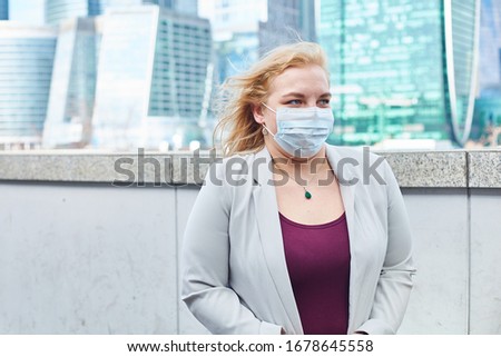 blonde girl stay at street near business center in a medical mask