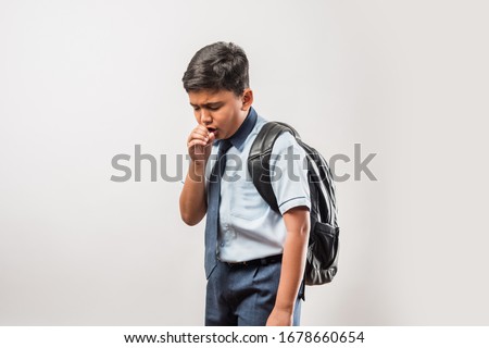 Indian school boy coughing while wearing school uniform and schoolbag, isolated over white background Royalty-Free Stock Photo #1678660654