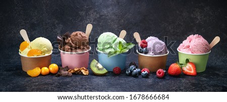 Various colorful ice cream in paper cup on dark rustic background