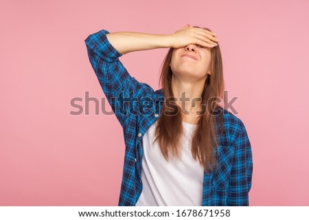 Portrait of unlucky girl in checkered shirt standing with facepalm gesture, feeling regret and sorrow, blaming herself for mistake, frustrated by defeat. indoor studio shot isolated on pink background Royalty-Free Stock Photo #1678671958