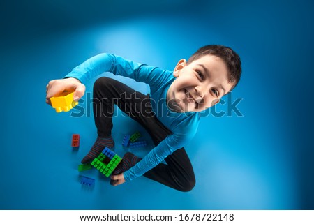 happy kid playing toy blocks isolated on the blue background.top view