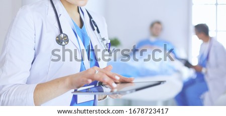 Female doctor using tablet computer in hospital lobby Royalty-Free Stock Photo #1678723417