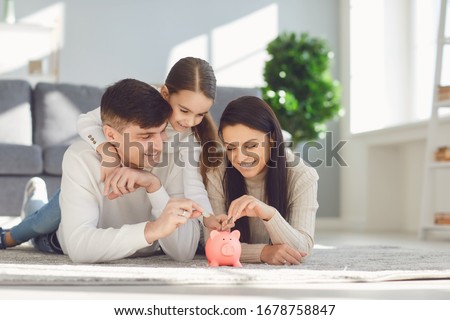 Happy family saves money in a piggy bank pig. Royalty-Free Stock Photo #1678758847