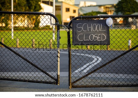 school closed sign with protective mask hanging on a padlocked gate, school closed or shutdown concept amid coronavirus fears and panic over contagious virus spread of the pandemic outbreak Royalty-Free Stock Photo #1678762111