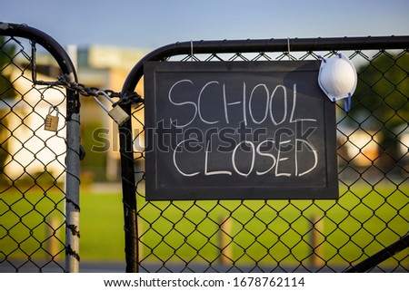 school closed sign with protective mask hanging on a padlocked gate, school closed or shutdown concept amid coronavirus fears and panic over contagious virus spread of the pandemic outbreak Royalty-Free Stock Photo #1678762114