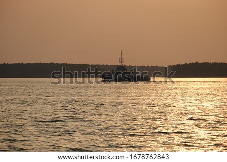 Silhouette picture of tugboat approaching a ship 