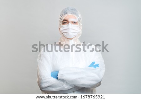 Man in protective suit, medical mask, goggles with arms crossed. Isolated in studio Royalty-Free Stock Photo #1678765921