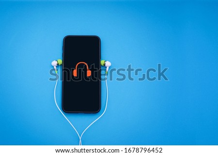 A hand phone with earphones and headphones icon on the screed.  A conceptual idea of 