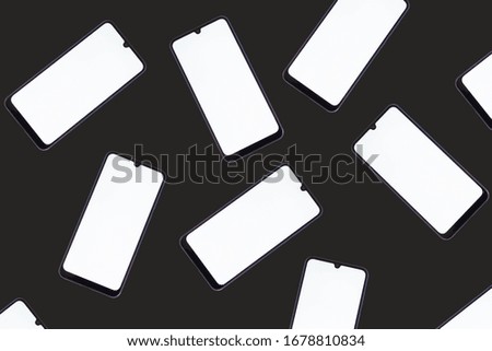 Smartphones with white screens are scattered on a black background..