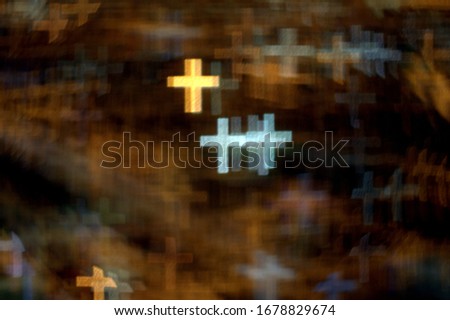 numerous golden and white crosses on a dark golden background of multiple crosses bokeh effect using a special camera lens filter