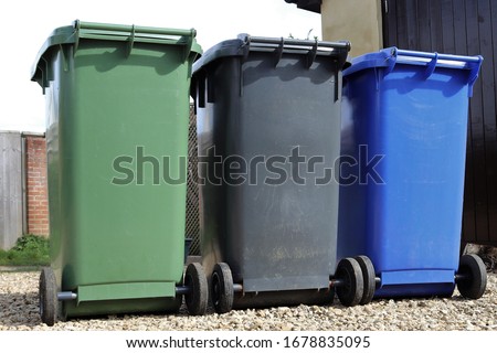 Household waste recycling sheme wheelie bins in Northamptonshire, England. Black for landfill, blue for recyclables and green for garden waste. Royalty-Free Stock Photo #1678835095