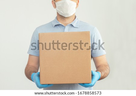 Delivery man holding cardboard boxes in medical rubber gloves and mask. copy space. Fast and free Delivery transport . Online shopping and Express delivery . Quarantine  Royalty-Free Stock Photo #1678858573